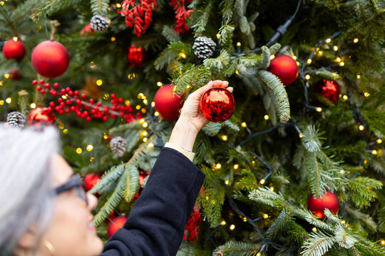 Woman decorating christmas tree with red ornament