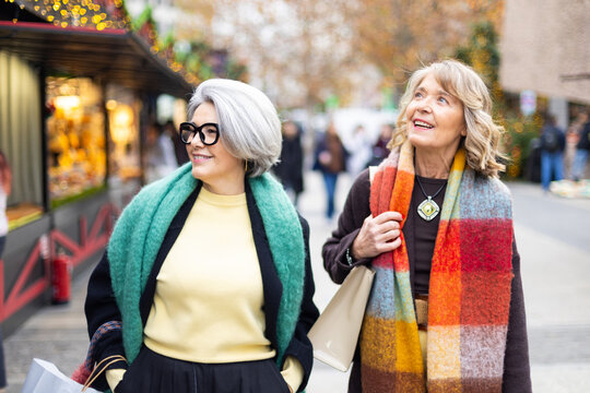 Senior women friends enjoying shopping at christmas market