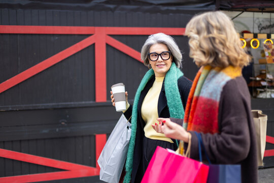 Senior women friends enjoying shopping and coffee together in city