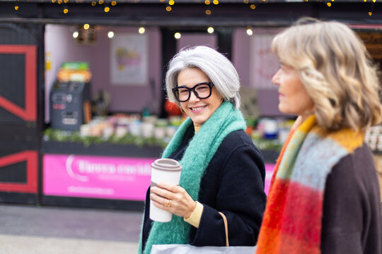 Mature woman smiling holding coffee cup outdoor market