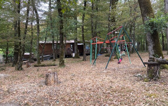 Children's swing made of logs and ropes and installed in the backyard of a rural house 