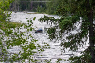 White spruce Picea glauca trees framing anglers fly fishing next to a drift boat in overcast daylight at Russian River Kenai Peninsula Alaska USA © Joao Vieira