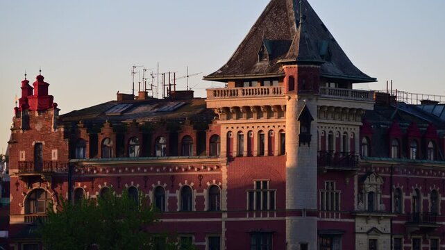 A red brick building with a corner tower and steep slate roof in early morning light, Prague, Czech Republic