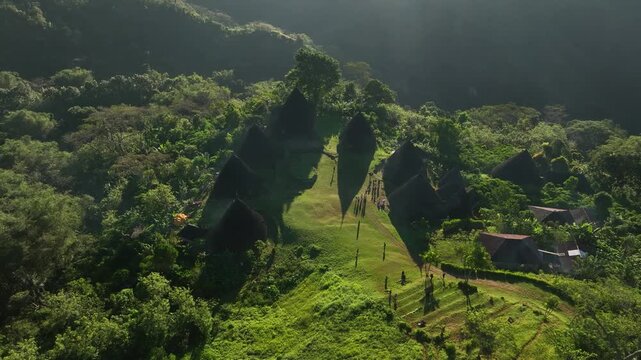 Aerial view of Waerebo Village with traditional conical houses nestled in the lush green mountains of Satar Mese Barat, East Nusa Tenggara, Indonesia.