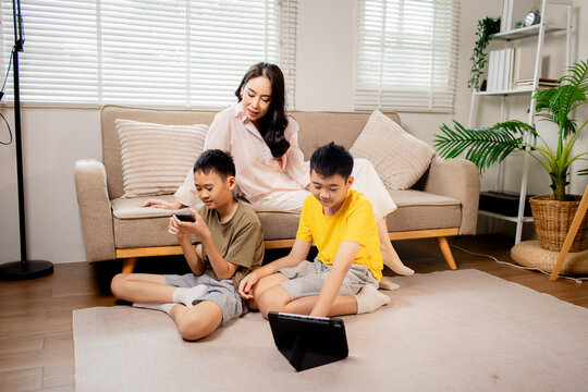 Mother teaching music to her children while playing guitar at home