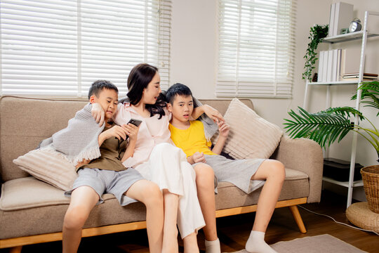 Mother teaching music to her children while playing guitar at home