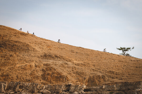 Group of cyclists riding mountain bikes down steep hill slope, outdoor adventure sport