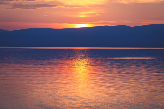 Sunset with golden reflection over calm waters of Lake Baikal, Siberia, Russia