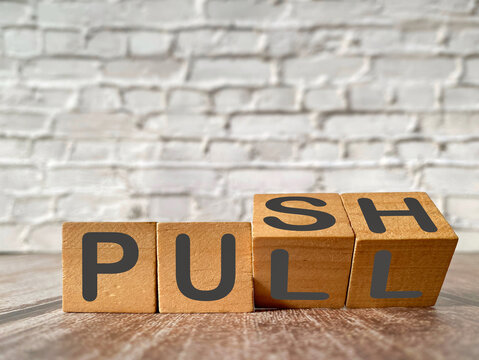 Wooden blocks illustrating push and pull as a business strategy concept, representing competing priorities, negotiation, influence and strategic decisions.