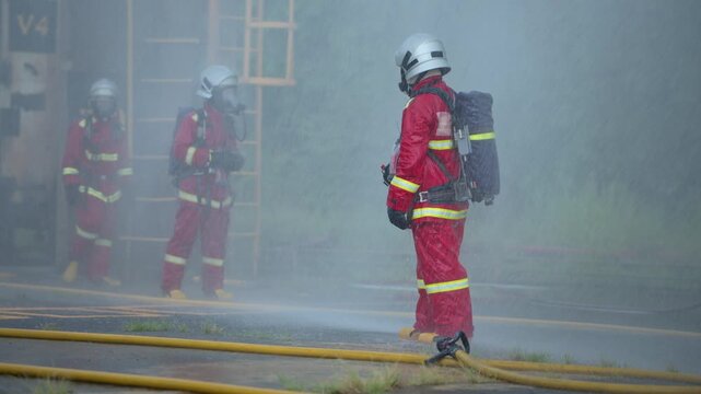 Firefighters use water hoses to control flames during a coordinated industrial fire suppression training exercise
