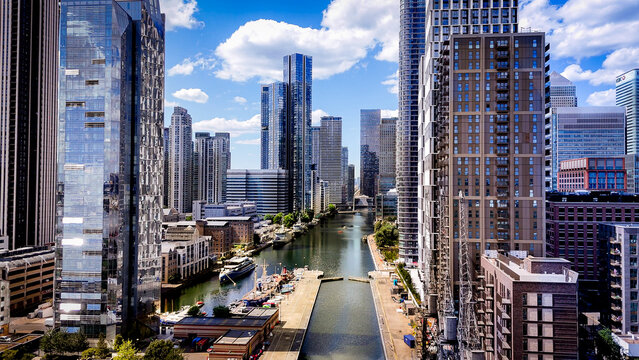 Aerial view between modern skyscrapers and waterways in Canary Wharf, showcasing the dense contemporary architecture of London's financial district.
