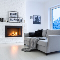 Fototapeta premium A cozy Scandinavian living room featuring a warm fireplace, a modern grey sofa, and a snowy winter view. Nobody present, evoking a peaceful, comfortable, and inviting mood.
