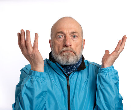 Portrait of a senior man with wide-open eyes and raised hands, expressing confusion, uncertainty, and indifference.