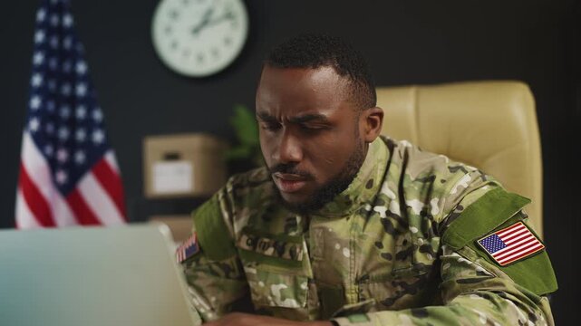 U.S. ranking army officer works on laptop, reviewing operational data