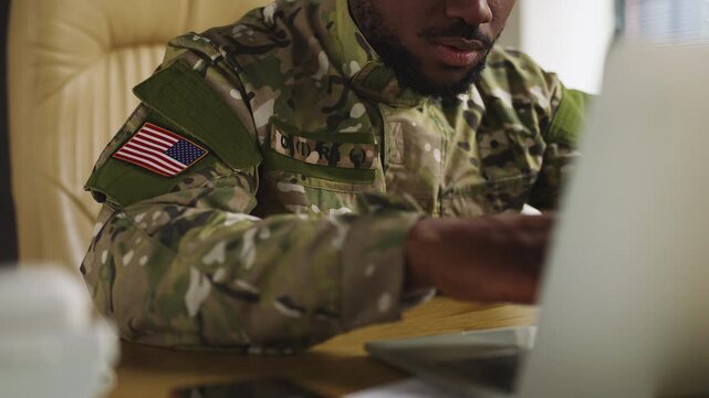 African American U.S. serviceman types on laptop, planning defense operations