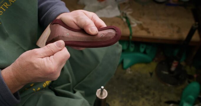 Shoemaker occupation. Diy manufacturing. Unrecognizable professional cobbler man hands working with leather material sole at workspace.