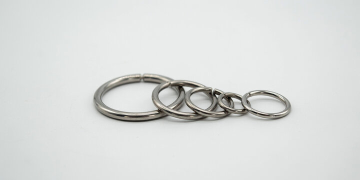 Five polished metal rings of varying sizes lined up on a white studio background
