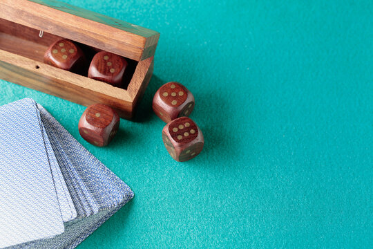 Playing cards and wooden dice on a green cloth.