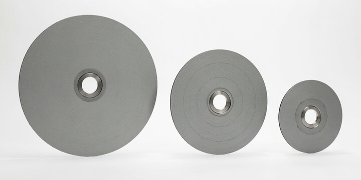 Three circular metal discs of varying sizes with center holes on white background