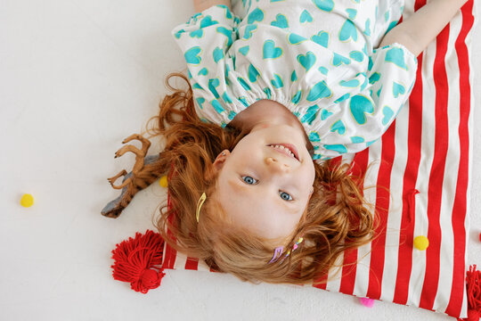 A girl lies and smiles on a multi-colored mattress