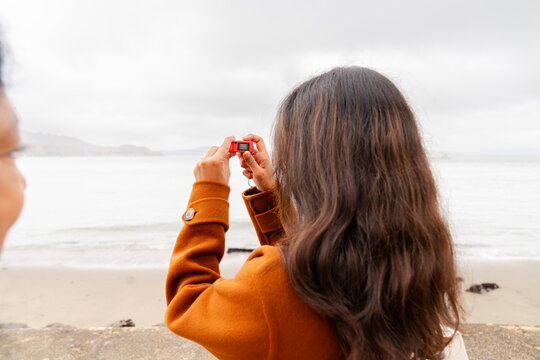 woman taking photo with small keychain charm camera 