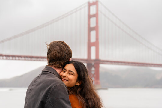 happy couple hugging together golden gate bridge san francisco 