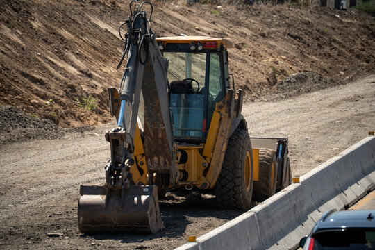 Heavy construction equipment backhoe loader parked on a dirt road at a site