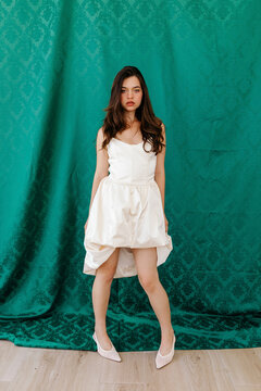 Fashion model in asymmetrical white dress and heels