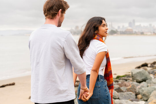 couple holding hands walking behind 