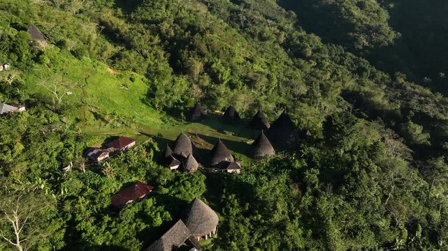 Aerial view of Waerebo Village with traditional conical houses nestled in lush green mountains in Satar Mese Barat, East Nusa Tenggara, Indonesia.