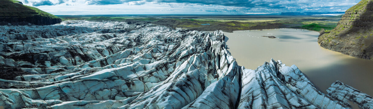 Sharp blue ice formations rise above the glacier lagoon at Skaftafellsj&ouml;kull in Vatnaj&ouml;kull National Park, surrounded by rugged mountains and Iceland's spectacular glacial landscape.