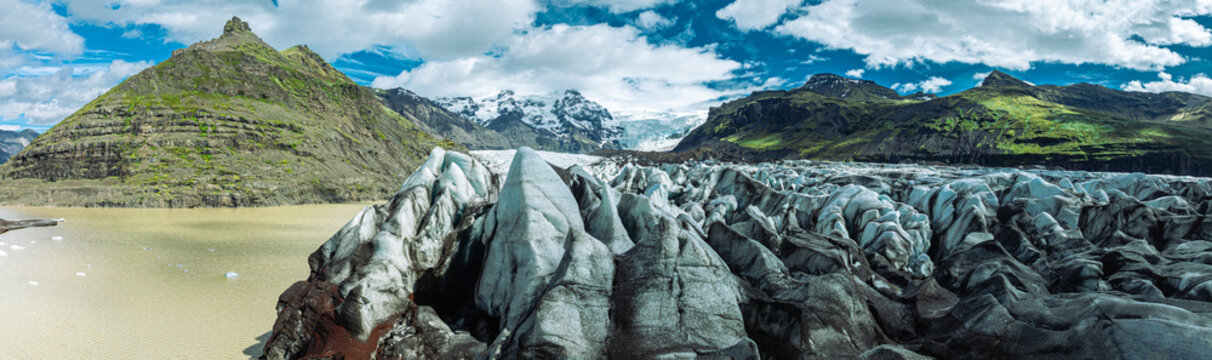 Sharp blue ice formations rise above the glacier lagoon at Skaftafellsj&ouml;kull in Vatnaj&ouml;kull National Park, surrounded by rugged mountains and Iceland's spectacular glacial landscape.