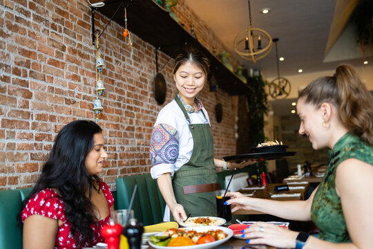 Waitress serving fresh plates to friends