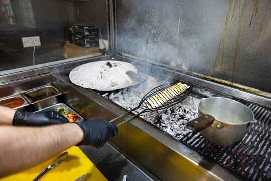 Chef grilling traditional Turkish kebab over hot charcoal
