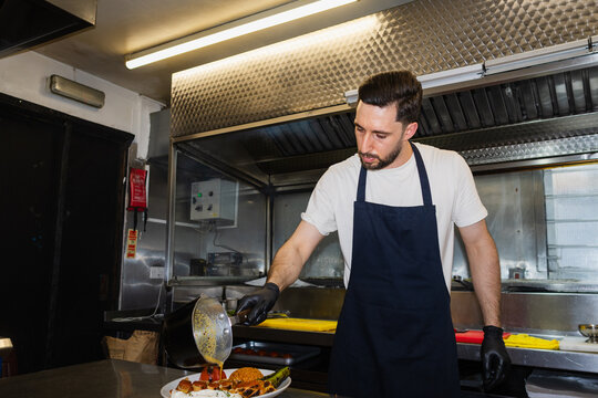 Chef pouring sauce over a traditional Turkish kebab plate