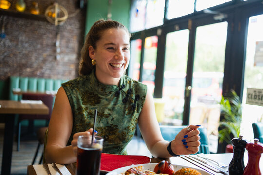 Candid portrait of a joyful millennial woman dining out