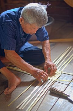 Elderly Man Weaves Bamboo Fan, Full Body, Rural Thailand