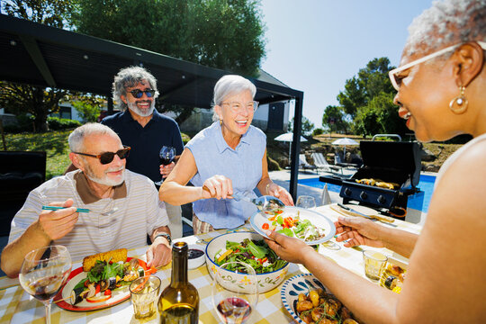 Seniors enjoying an outdoor barbecue lunch by the pool