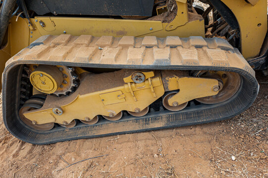 Heavy duty rubber continuous track and undercarriage on a yellow skid steer loader at a construction site