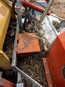 Close view of dirty hydraulic equipment and grass on yellow excavator at work site