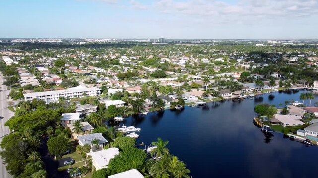 Aerial view drone video of a residential neighborhood, houses near lake with pools, cars, boats, bridges, tropical plants, palm trees, Pompano Beach Fl USA Miami beach, sunny day