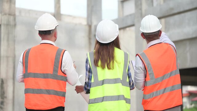 Architects and construction engineers review structural and architectural plans at a building site. Concept of construction planning, structural design, teamwork, and project development.