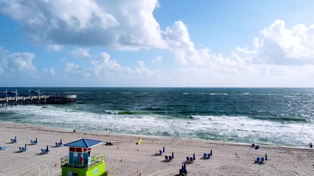 Aerial view drone video of Beach guard house Pompano Beach and Pier in background, blue ocean and sea waves FL USA Miami beach, sunny day, sky blue EEUU 4k