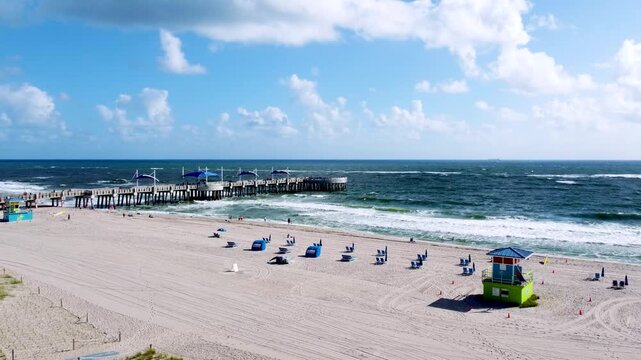 Aerial view drone video of Beach guard house Pompano Beach and Pier in background, blue ocean and sea waves FL USA Miami beach, sunny day, sky blue EEUU 4k