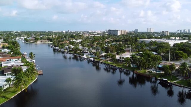 Aerial view drone video of a residential neighborhood, houses near lake with pools, cars, boats, bridges, tropical plants, palm trees, Pompano Beach Fl USA Miami beach, sunny day.