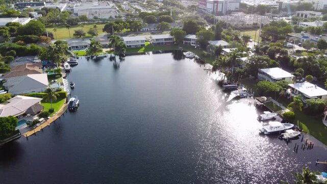 Aerial view drone video of a residential neighborhood, houses near lake with pools, cars, boats, bridges, tropical plants, palm trees, Pompano Beach Fl USA Miami beach, sunny day.