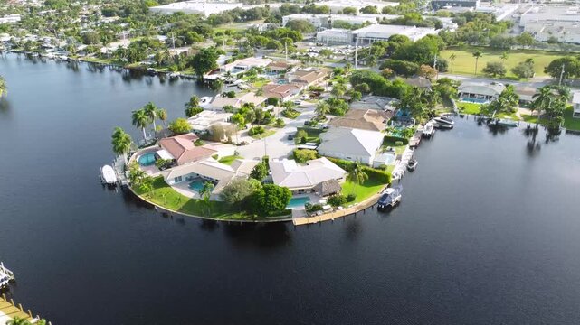 Aerial view drone video of a residential neighborhood, houses near lake with pools, cars, boats, bridges, tropical plants, palm trees, Pompano Beach Fl USA Miami beach, sunny day