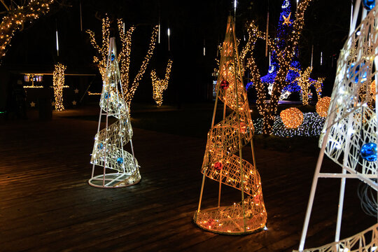 Light Christmas decorations shine at night in a garden setting during a holiday festival
