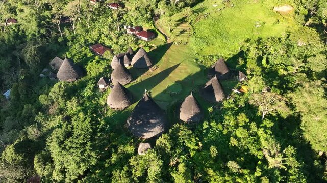 Aerial view of Waerebo Village with traditional conical houses surrounded by lush green mountains in Satar Mese Barat, East Nusa Tenggara, Indonesia.