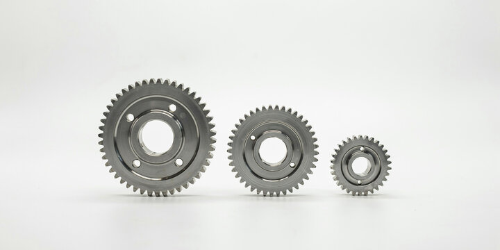 Three industrial metal gears of different sizes on a white background